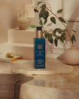 Balsam do rąk Rituals Hammam w butelce z pompką ustawiony na marmurowym blacie w łazience