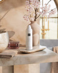 Rituals żel do mycia ciała Sakura w formie pianki obok kwiatów sakury na kamiennym blacie w łazience