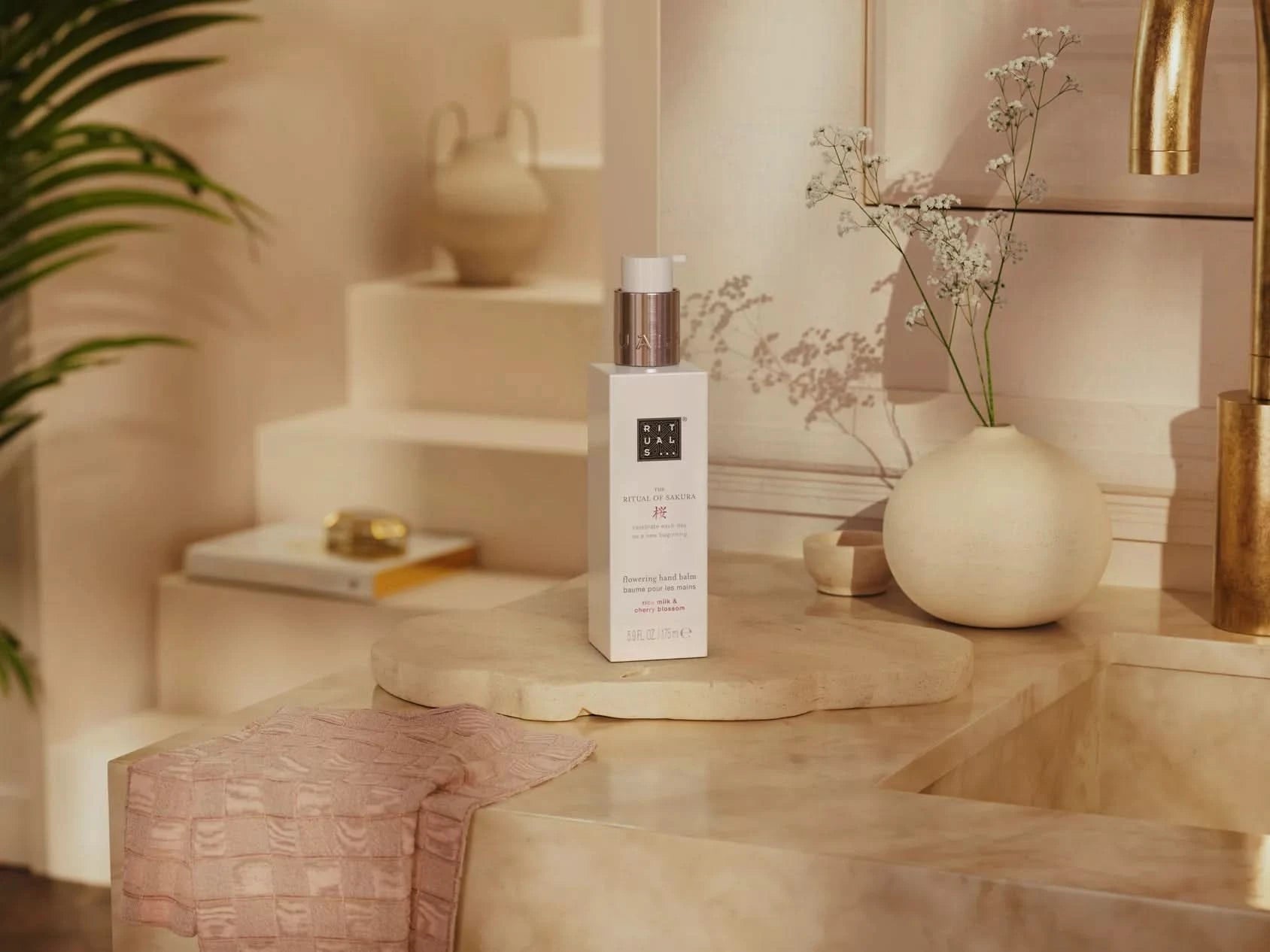 Balsam do rąk Rituals Sakura w eleganckim opakowaniu na kamiennym blacie z dekoracją