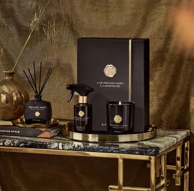 Zestaw podarunkowy kosmetyki Rituals dla firm z zapachem Precious Amber na eleganckim złotym stoliku