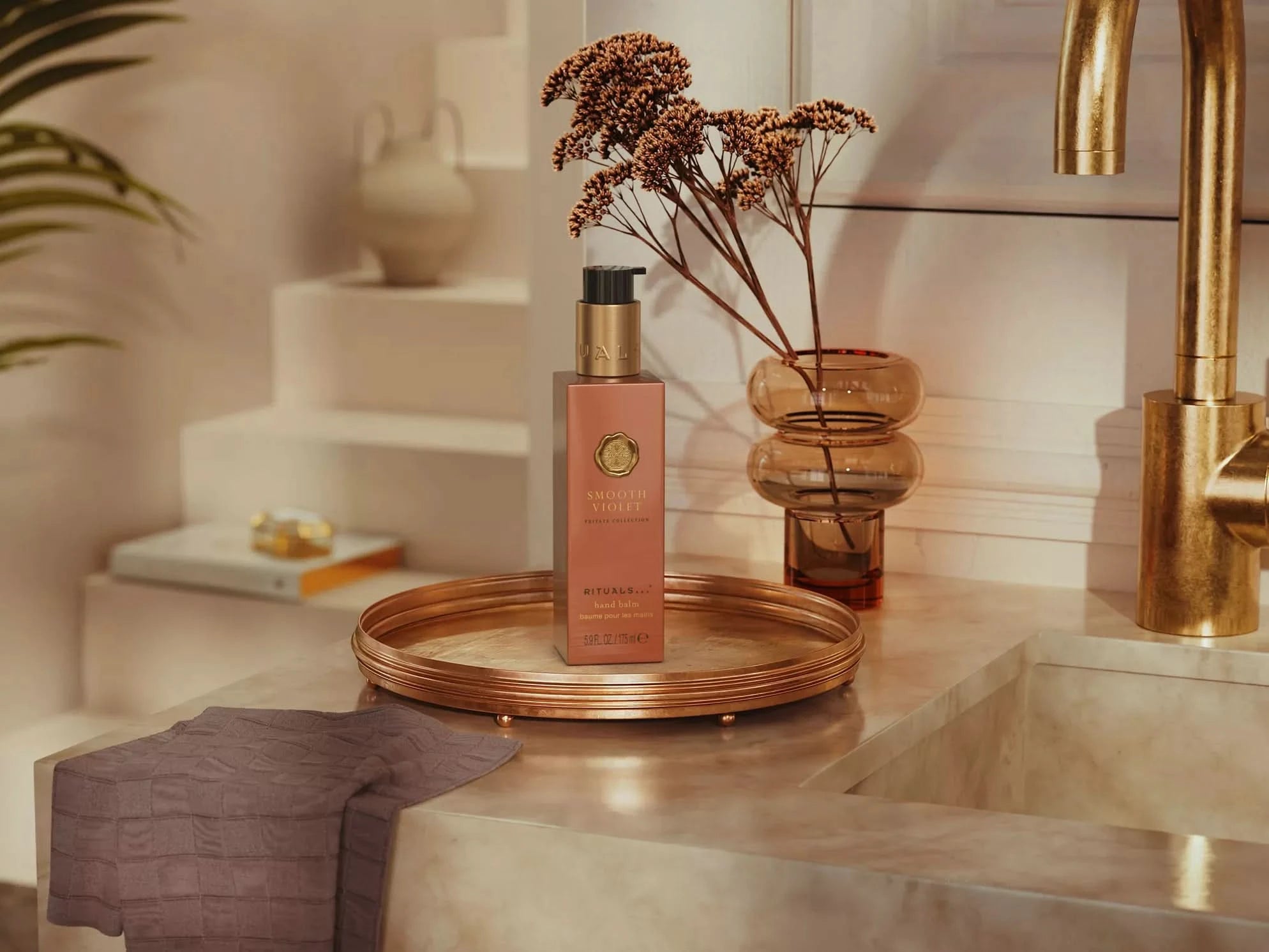 PRIVATE COLLECTION balsam do rąk Rituals na złotej tacy obok suszonych kwiatów w eleganckiej łazience