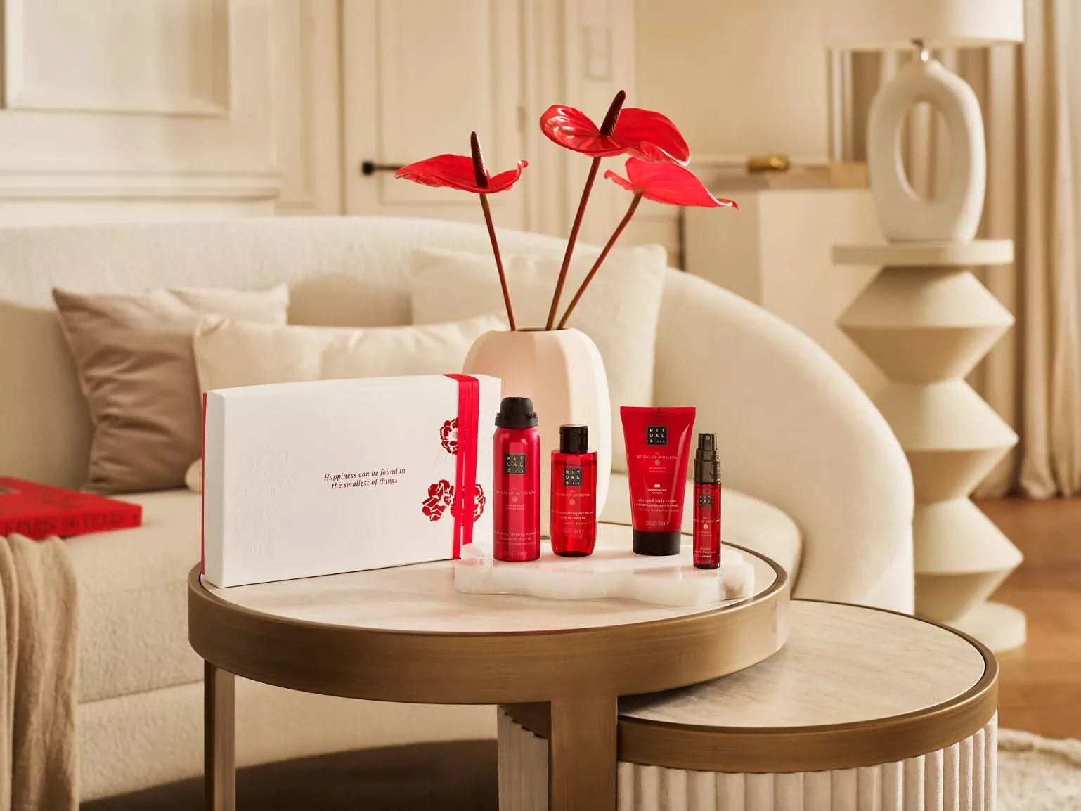 Rituals the ritual of ayurveda zestaw upominkowy z kosmetykami w czerwonych opakowaniach na stoliku w salonie