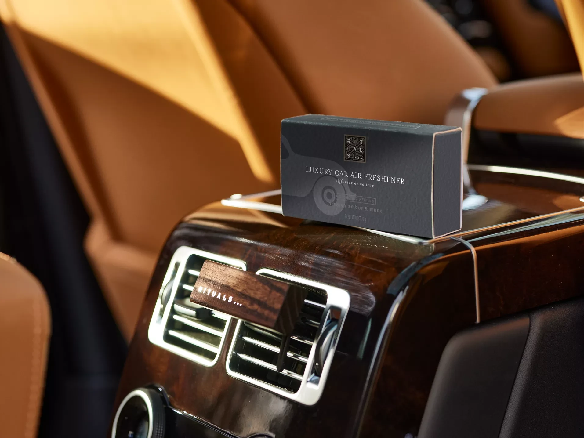 Rituals zapach do samochodu dla firm na konsoli samochodu z drewnianym wykończeniem i brązową tapicerką