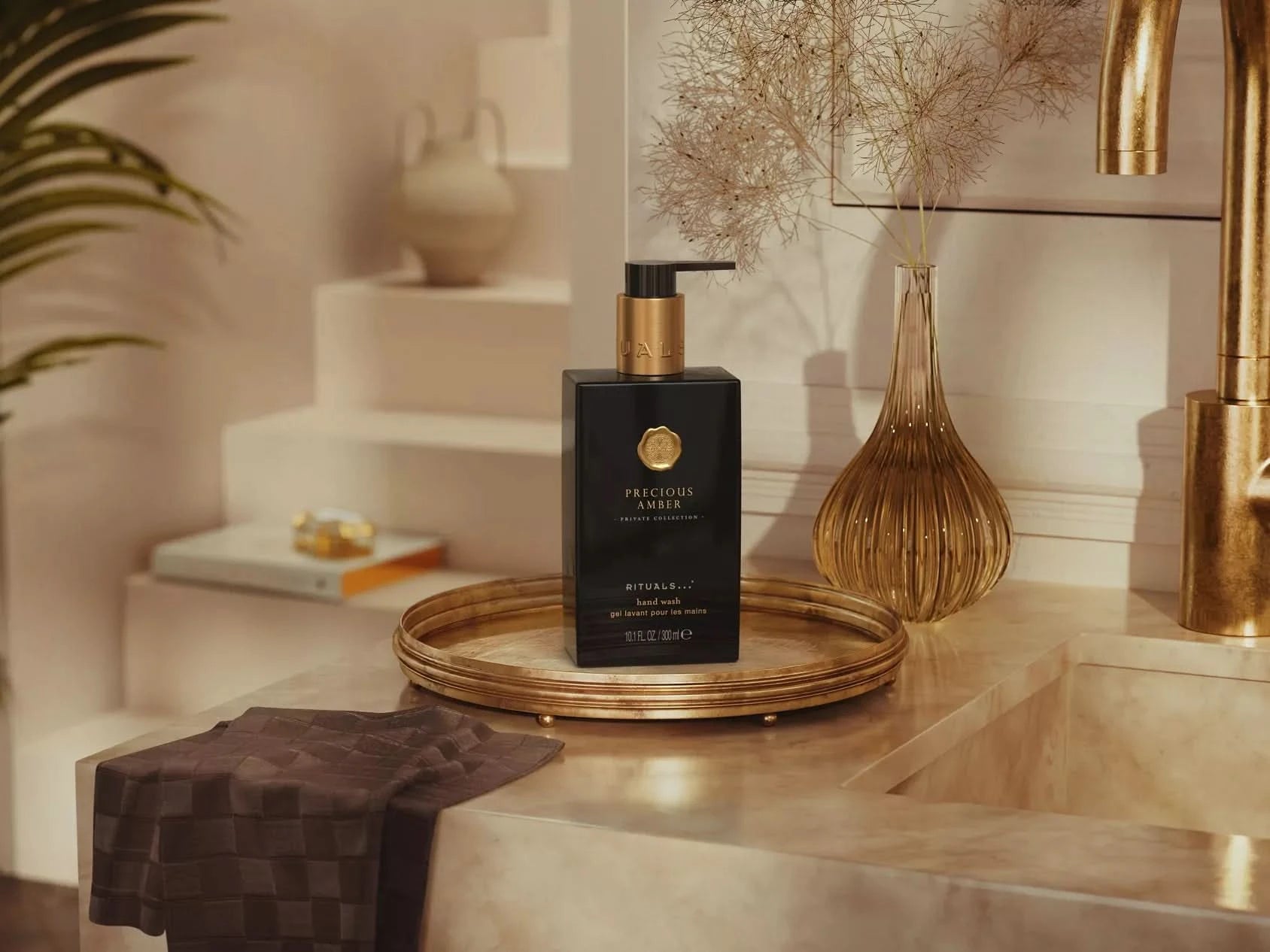 Żel do mycia rąk Rituals Precious Amber w czarnej butelce z pompką na marmurowej łazienkowej umywalce