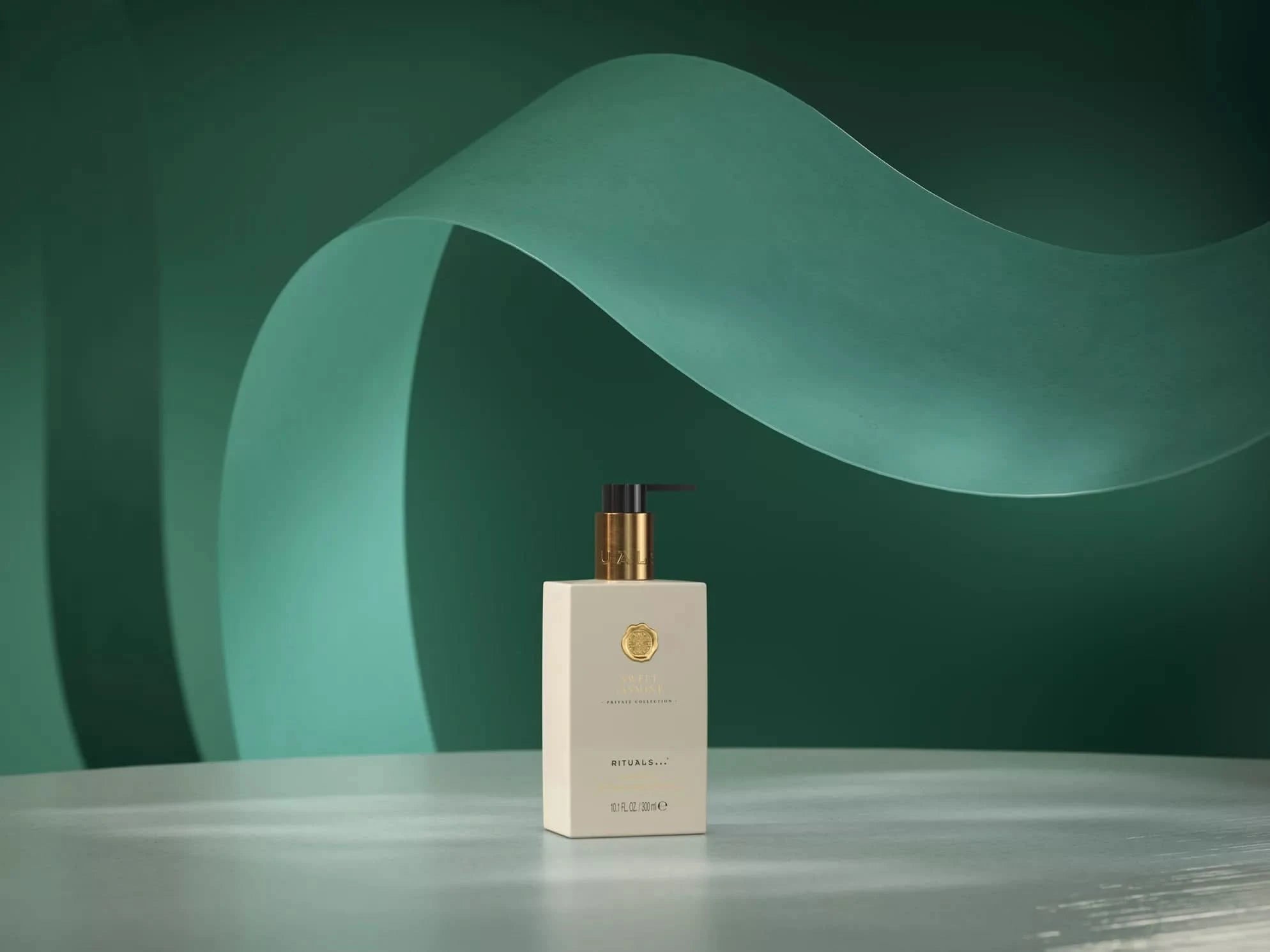 Butelka żelu do mycia rąk Rituals Sweet Jasmine z dozownikiem na zielonym tle z dekoracyjną falą