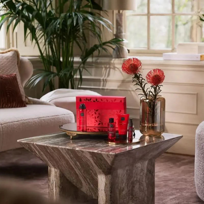 Zestaw prezentowy Rituals dla firm na stoliku w eleganckim salonie z czerwonym opakowaniem i kosmetykami
