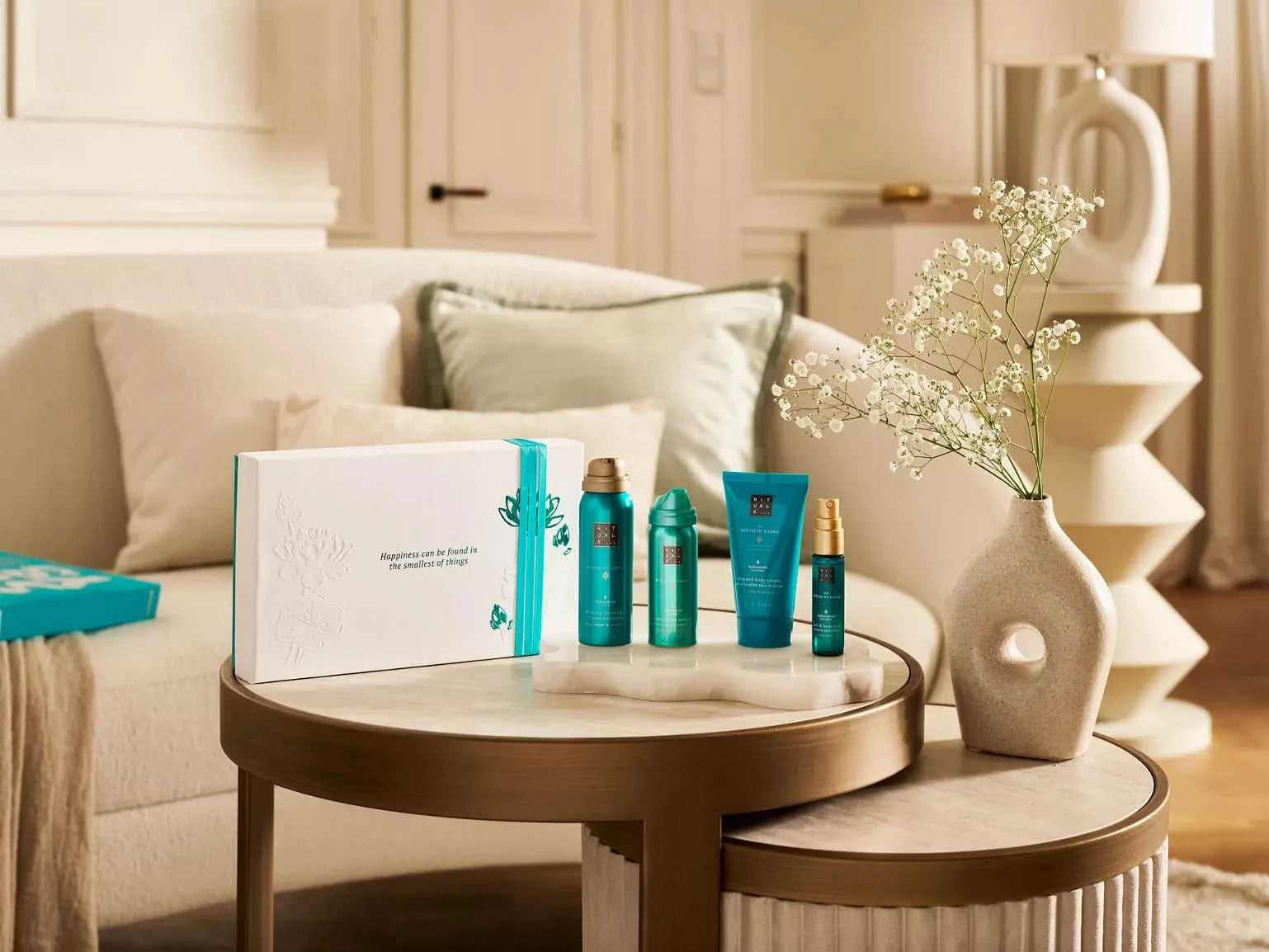 Zestaw upominkowy Rituals dla firm z kosmetykami w niebieskich opakowaniach na stoliku w salonie