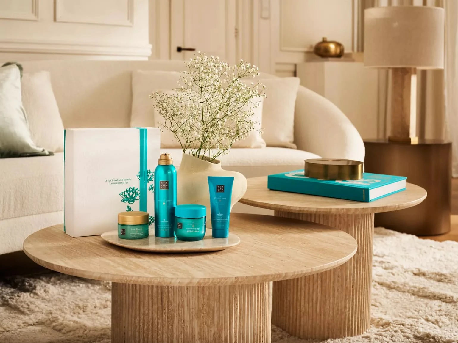 Zestaw upominkowy Rituals Karma dla firm z kosmetykami do pielęgnacji ciała na drewnianym stoliku w salonie