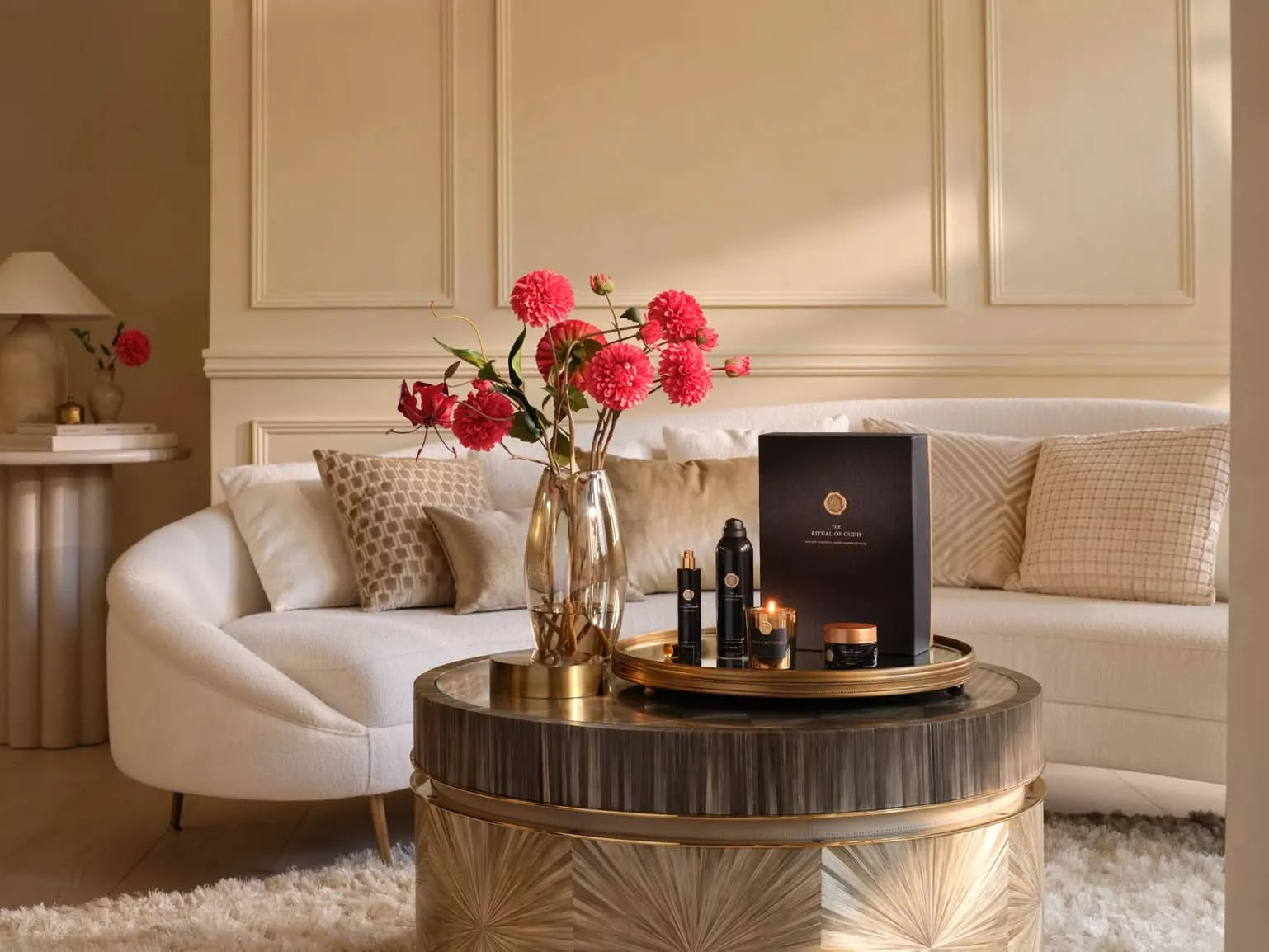 Zestaw upominkowy Rituals Precious Amber na stoliku kawowym z kwiatami w eleganckim salonie