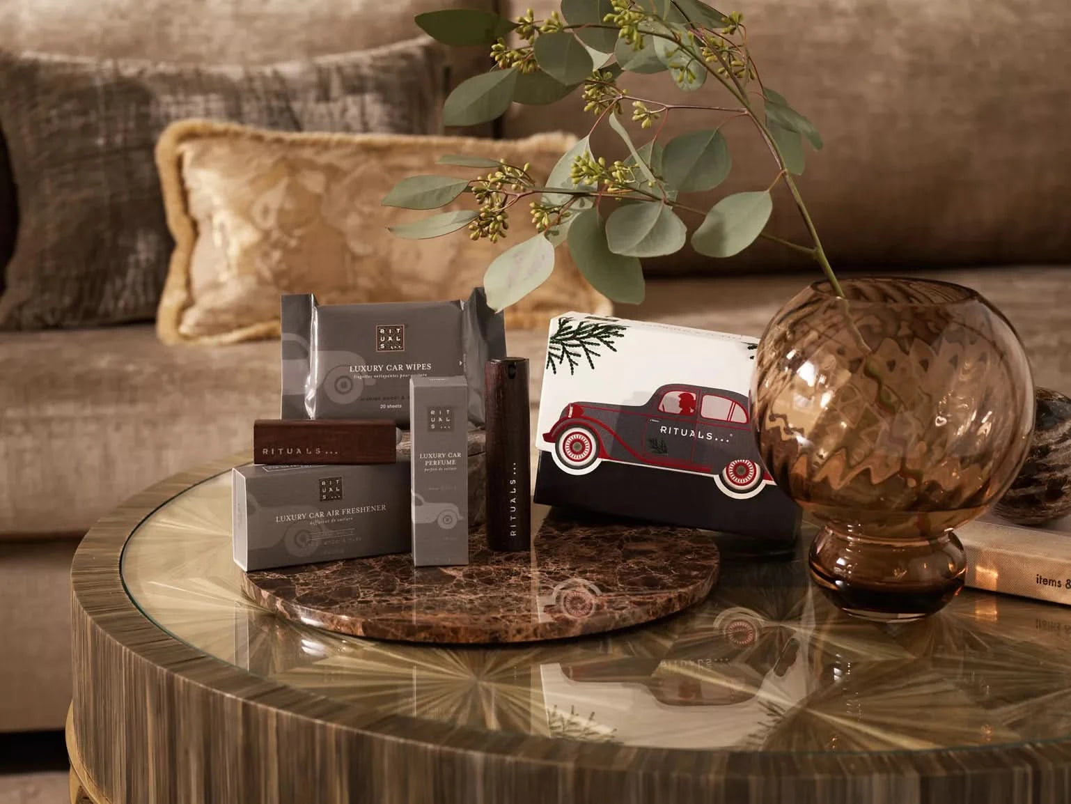 Elegancki zestaw upominkowy samochodowy Rituals z kosmetykami na szklanym stoliku w salonie